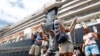 Passengers react after they disembark from the MS Westerdam, back, at the port of Sihanoukville, Cambodia, Friday, Feb. 14, 2020. Hundreds of cruise ship passengers long stranded at sea by virus fears cheered as they finally disembarked Friday and were welcomed to Cambodia.