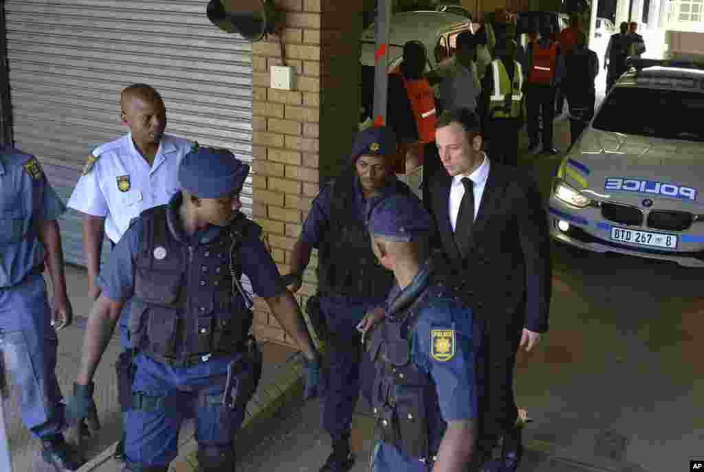 Oscar Pistorius is led to a awaiting police vehicle to be taken to prison, in Pretoria, South Africa, Oct. 21, 2014. 