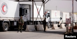 Russian soldiers are seen securing Syrian Arab Red Crescent trucks carrying aid at a checkpoint near Wafideen camp in Damascus, March 5, 2018.