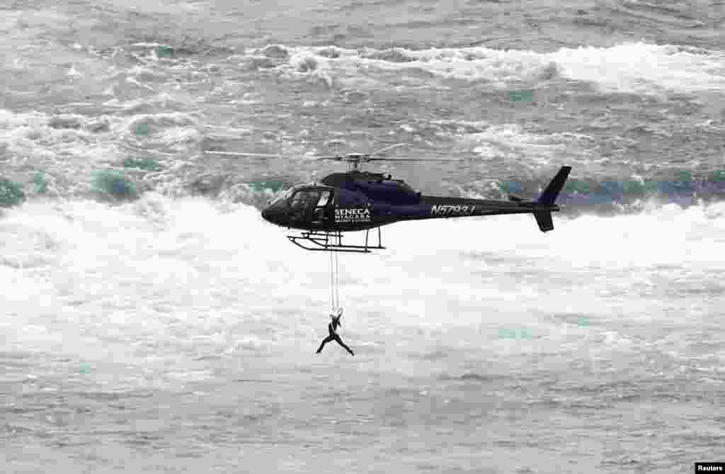 Trapeze artist Erendira Wallenda performs as she hangs from a helicopter flying over the American side of Niagara Falls, in Niagara Falls, New York.