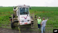 FILE - A corn farmer confers with a fellow farmer while refilling his sprayer with the weed killer glyphosate on a farm near Auburn, Ill. 