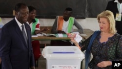 FILE - Ivory Coast's President Alassane Ouattara, left, and his wife, Dominique Ouattara, cast their ballots during the Ivory Cost referendum in Abidjan, Ivory Coast, Oct. 30, 2016.