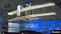 Una réplica de la aeronave de los hermanos Wright planea encima de la audiencia durante la ceremonia por el 100 aniversario del primer vuelo celebrado en el centro Steven F. Udvar-Hazy del Museo del Aire y del Espacio del Smithsonian.
