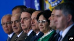 Brazil's President Jair Bolsonaro, center, and his ministers attend the launch of the Green and Yellow program to create formal jobs for young people, at the Planalto Presidential Palace, in Brasilia, Brazil, Nov. 11, 2019.