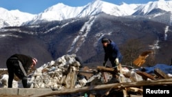 Workers start cleaning the area next to an unfinished hotel in the mountain media village on top of the village of Esto Sadok at the Rosa Khutor alpine resort near Sochi, February 2, 2014. Sochi will host the 2014 Winter Olympic Games from February 7 to 2