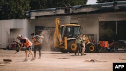 This handout photograph taken and released by Dnipropetrovs’k Regional Military Administration on July 3, 2024, shows communal workers clearing debris following a Russian strike in the city of Dnipro, amid the Russian invasion of Ukraine.