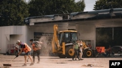 This handout photograph taken and released by Dnipropetrovs’k Regional Military Administration on July 3, 2024, shows communal workers clearing debris following a Russian strike in the city of Dnipro, amid the Russian invasion of Ukraine.