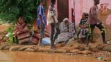 FILE - Sudanese residents sit outside their house at the flooded area of Alqamayir in the capital's twin city of Omdurman, Aug. 26, 2020.