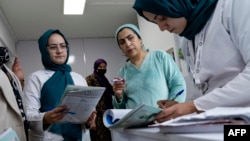 (FILE) This photograph taken on December 10, 2024 shows Dr. Najmussama Shefajo along with other female midwives and nurses, checking the documents of pregnant women at her private hospital in Kabul.