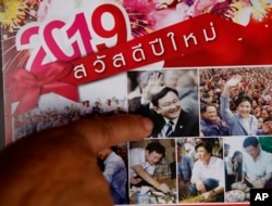 In this March 14, 2019, photo, Nuwate Jiamwong, the 59-year-old farmer, points at an image of former Prime Minister Thaksin Shinawatra on a calendar in Nakhon Ratchasima, Thailand.