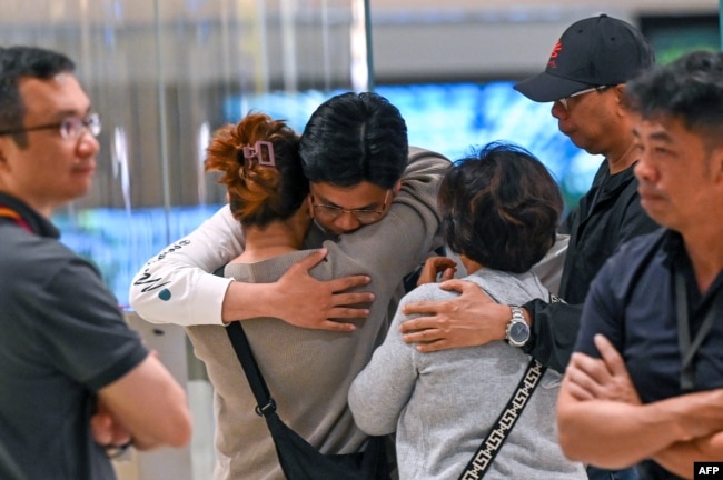 Passengers of Singapore Airlines flight SQ321 from London to Singapore, which made an emergency landing in Bangkok, greet family members upon arrival at Changi Airport in Singapore on May 22, 2024. (Photo by Roslan RAHMAN / AFP)