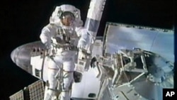 Spacewalker Bowen moves into position aboard the International Space Station's robotic arm as he works outside the station in this image from NASA TV, February 28, 2011