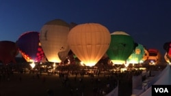 During twilight at the Albuquerque International Balloon Fiesta, spectators can see balloons light up in unison, creating a beautiful orchestra of light. (J.Taboh/VOA)