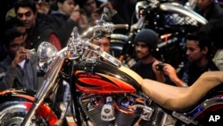 FILE - Indians take photos of a Harley Davidson motorcycle during the Auto Expo in New Delhi, Jan. 7, 2012. India says it will cut duties on a range of imports that could help increase American imports to India, including high end motorcycles and cars.