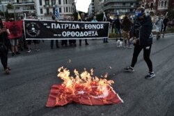 Protesters burn a Turkish national flag outside of a church during a gathering in Thessaloniki, July 24, 2020, against turning the historic Hagia Sophia in Istanbul to a mosque after serving for more than 80 years as museum.