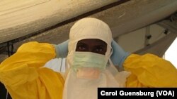 Un agent de santé ajustant son équipement de protection dans un centre de traitement d’Ebola géré par Médecins sans frontières (MSF) à Conakry, en Guinée. (VOA / Carol Guensburg)