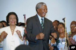 FILE- Nelson Mandela, and Coretta Scott King, left, widow of slain civil rights leader Martin Luther King, Jr., sing and dance at a victory celebration for Mandela in Johannesburg, on May 2, 1994.