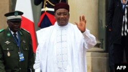 Le président nigérien Mahamadou Issoufou salue alors qu'il quitte l'Elysée après la conférence internationale sur la Libye, à Paris, le 29 mai 2018.