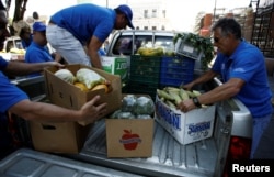 Men carry boxes with agricultural products donated for needy people by fruit and vegetables vendors from markets as part of Holy Week in San Jose, Costa Rica, April 12, 2017.