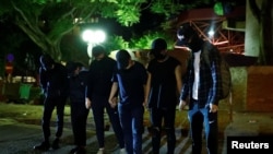 Anti-government protesters wait to give themselves up to the police as they leave the campus of the Polytechnic University in Hong Kong, Nov. 21, 2019. 