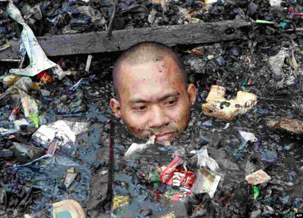 April 7: A man wades in neck-deep sea water filled with debris while searching for valuable items after a fire razed more than 500 houses along a village in Malabon city, north of Manila. The fire, believed to be caused by an exploding liquefied petroleu