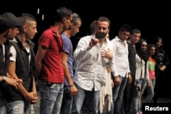 Director Lucien Bourjeily (C) talks alongside youth actors from Tripoli, North Lebanon, after their performance in a play he directed in Beirut, July 28, 2015.