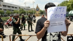一名泰國學生星期五在曼谷街頭舉起抗議軍方的行動標語牌，表達不滿。