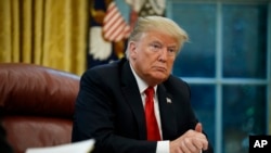 FILE - President Donald Trump listens to a question during an interview in the Oval Office of the White House, in Washington, Oct. 16, 2018.