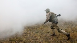 A reservist of the Ukrainian Territorial Defense Forces runs amidst smoke while taking part in military exercises at a training ground outside Kharkiv, Ukraine Dec. 11, 2021.