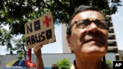 Una mujer sostiene un cartel que reza "no más abusos" durante una protesta contra el gobierno del presidente Nicolás Maduro, frente a la oficina del PNUD en Caracas, el 21 de junio de 2019. [Foto: AP]