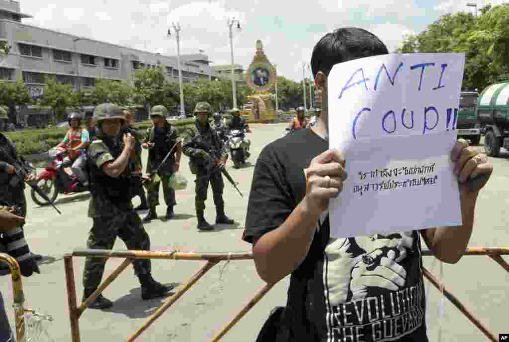 A Thai student holds an anti-coup sign in front of a group of soldiers during a brief protest near the Democracy Monument in Bangkok, May 23, 2014.