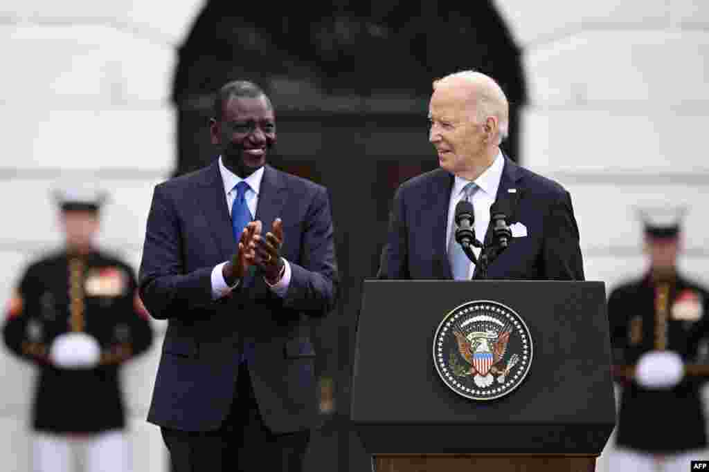 O Presidente dos EUA, Joe Biden (à direita), fala enquanto o Presidente do Quénia, William Ruto (à esquerda), aplaude durante uma cerimónia oficial de chegada ao relvado sul da Casa Branca em Washington, DC, a 23 de maio de 2024.