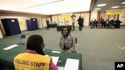 A Southern Sudanese woman smiles as she has her identification documents checked by an official before casting her vote for the Southern Sudan Referendum in a special polling station set up in central London, 09 Jan 2011.