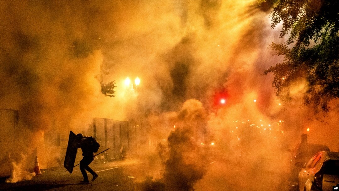 Un manifestante usa un escudo para protegerse de los químicos irritantes lanzados por agentes federales en la madrugada del 24 de julio.