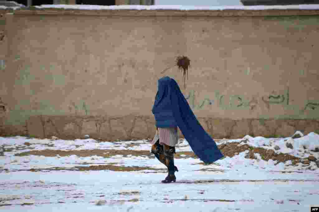 An Afghan woman walks along a street following a snowfall on the outskirts of Mazar-i-Sharif.