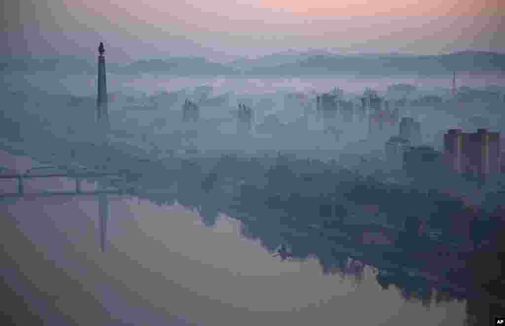 Dawn breaks over Pyongyang, North Korea, as buildings poke through the midst and the Juche Tower, left, stands by the Taedong riverbank.