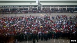 Migran Myanmar menunggu kedatangan Menlu Myanmar Aung San Suu Kyi, di tengah guyuran hujan di Talad Talay Thai, provinsi Samut Sakhon, Thailand (23/6).