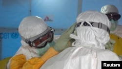 Dr. Joel Montgomery, team leader for the U.S. Centers for Disease Control and Prevention Ebola Response Team in Liberia, adjusts a colleague's personal protective equipment before entering the Ebola treatment unit in Monrovia, Liberia, Sept. 16, 2014. 