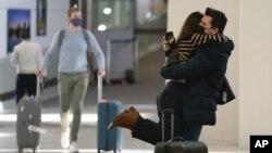 Natalia Abrahao is lifted up by her fiancé Mark Ogertsehnig as they greet one another at Newark Liberty International Airport in Newark, N.J., Monday, Nov. 8, 2021.