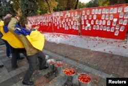 FILE - Activists throw tomatoes at portraits of lawmakers, who were absent during voting on anti-corruption laws, outside the Ukrainian parliament in Kyiv, Oct. 7, 2014. Some observers say incompetence is partly to blame for the lack of progress in Ukraine's efforts to root out corruption.