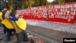 FILE - Activists throw tomatoes at portraits of parliamentary deputies who were absent from voting on anti-corruption laws, Kyiv, Oct. 7, 2014.