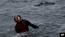 A Syrian refugee gasps for air after swimming to the shore from an inflatable boat near the coast of the island of Lesbos, Greece. (AP)