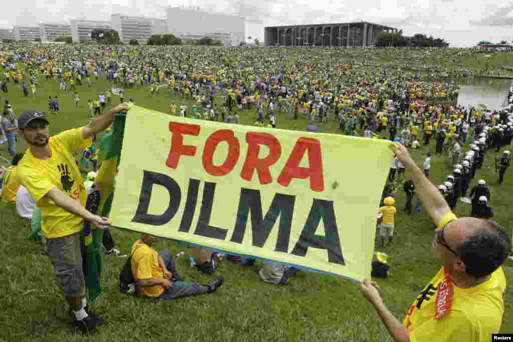 Cidadãos seguram placas de slogans contra o governo de Dilma Rousseff