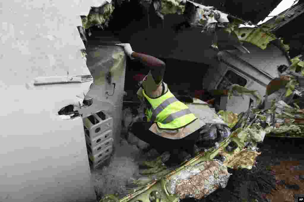A rescue worker inspects the wreckage of a charter passenger jet that crashed soon after take off from Lagos airport, Nigeria, Oct. 3, 2013. 