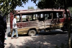 A boy walks past the wreckage of a bus following a suicide bombing in Kabul on July 25, 2019.