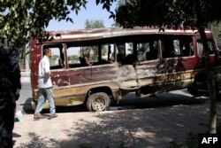 A boy walks past the wreckage of a bus following a suicide bombing in Kabul on July 25, 2019.