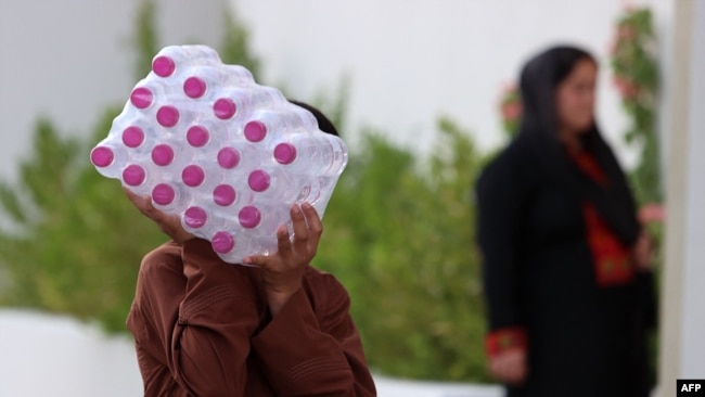 Seorang pria Afganistan membawa botol-botol air minum di sebuah kompleks penampungan pengungsi Afghanistan di Doha, Sabtu, 20 Agustus 2021. 