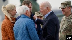 Prezidan Joe Biden salye ansyen gouvènè Steve Besheer (2e a goch) Gouvènè Kentucky Andy Beshear (3e a goch) ak madanm ni Britainy apre li rive nan Fort Campbell, eta Kentucky, Mekredi 15 Desanm.