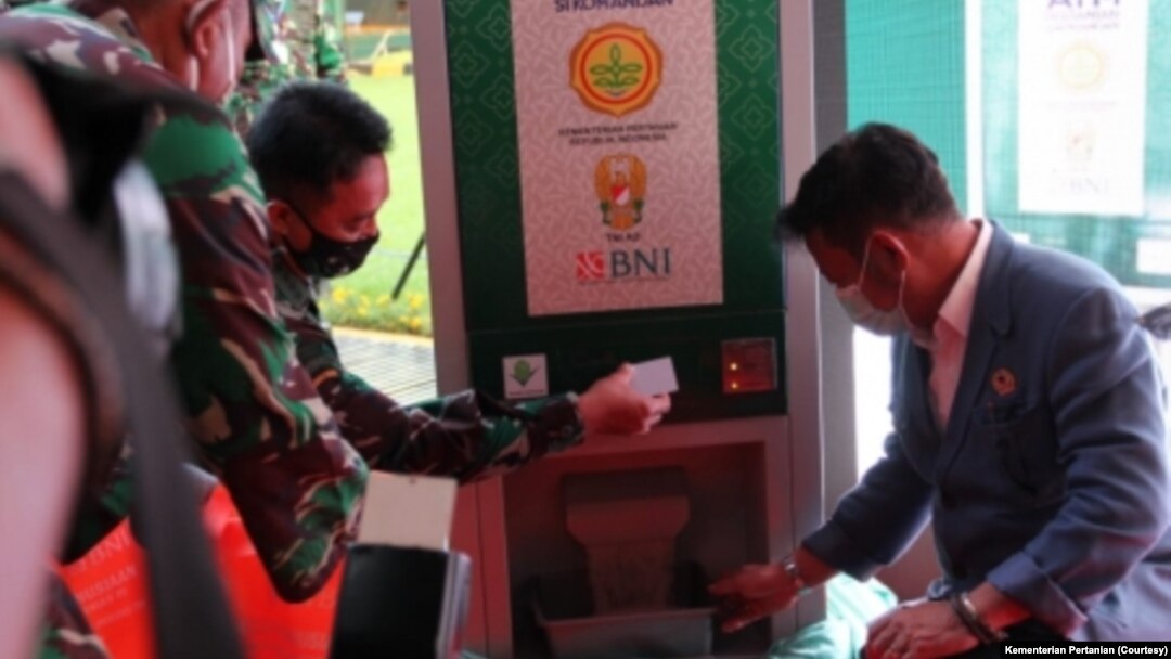 Dua orang mencoba menggunakan ATM beras. (Foto: Kementerian Pertanian)