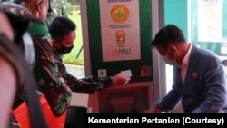 Dua orang mencoba menggunakan ATM beras. (Foto: Kementerian Pertanian)